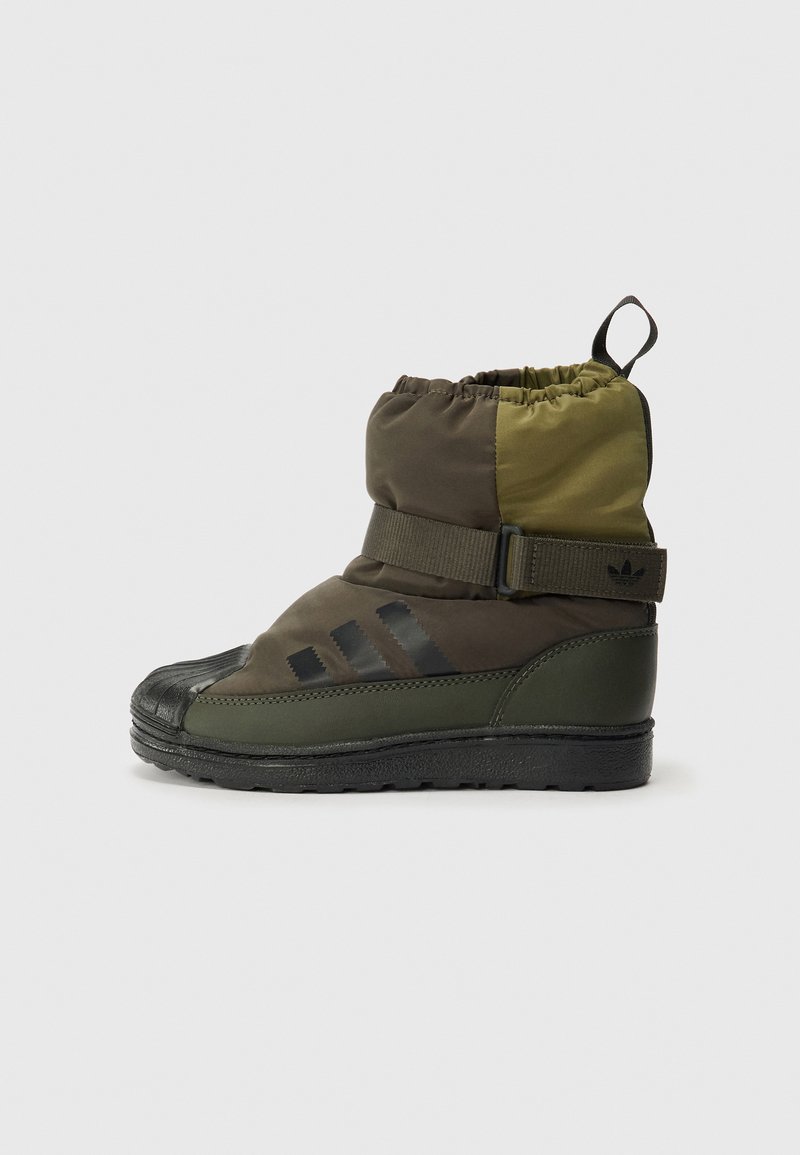 Bota impermeável verde e castanha com parte superior ajustável por cordão, biqueira de borracha e sola texturizada. Apresenta listras pretas e alça ajustável.