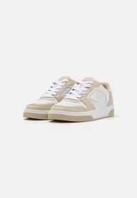 Sneaker beige e bianche con pannelli perforati, design con lacci e suola in gomma testurizzata. Materiale liscio con dettagli sui lati.