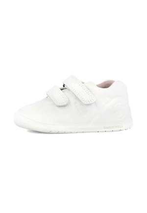 Zapatilla blanca con una textura suave, correas de velcro, punta redondeada y suela de goma. Cuenta con un logotipo en el lateral y un diseño minimalista.