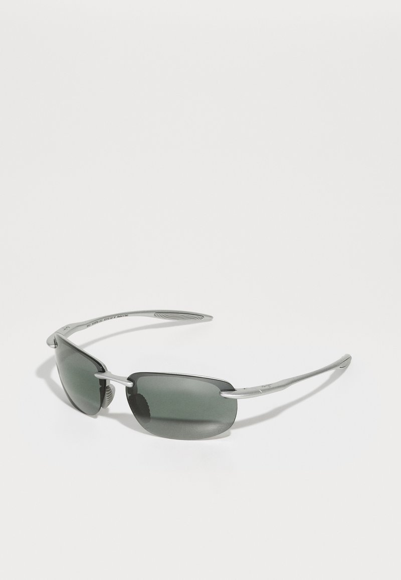 Lunettes de soleil avec des verres gris et des montures en métal argenté. Elles présentent une forme rectangulaire et des branches fines avec des accents texturés.