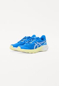 Baskets de course bleues avec tige en mesh, semelle jaune et accents argentés. Présente un col rembourré et des lacets pour un maintien sécurisé.