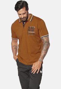 Braunes Polohemd mit einem marineblauen Kragen und Akzentstreifen. Verfügt über bedruckten Text auf der Brust in verschiedenen Schriftgrößen und -stilen. Kurzarm.