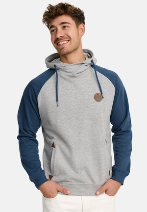 Sudadera con capucha en gris y azul marino, con mangas raglán, que presenta una capucha con cordón, detalle del logo en cuero y acentos triangulares en contraste.