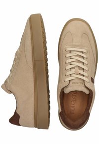 Zapatillas de ante beige con punta redonda, suela de goma plana y cordones a juego. Detalles en marrón cerca del talón y marca grabada en el interior.