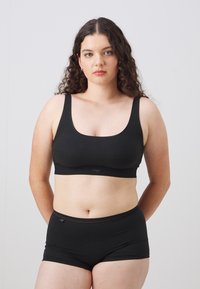 Black cotton blend bralette with wide straps and a rounded neckline, paired with matching black boyshorts. Soft, stretchy fabric with minimal seams.