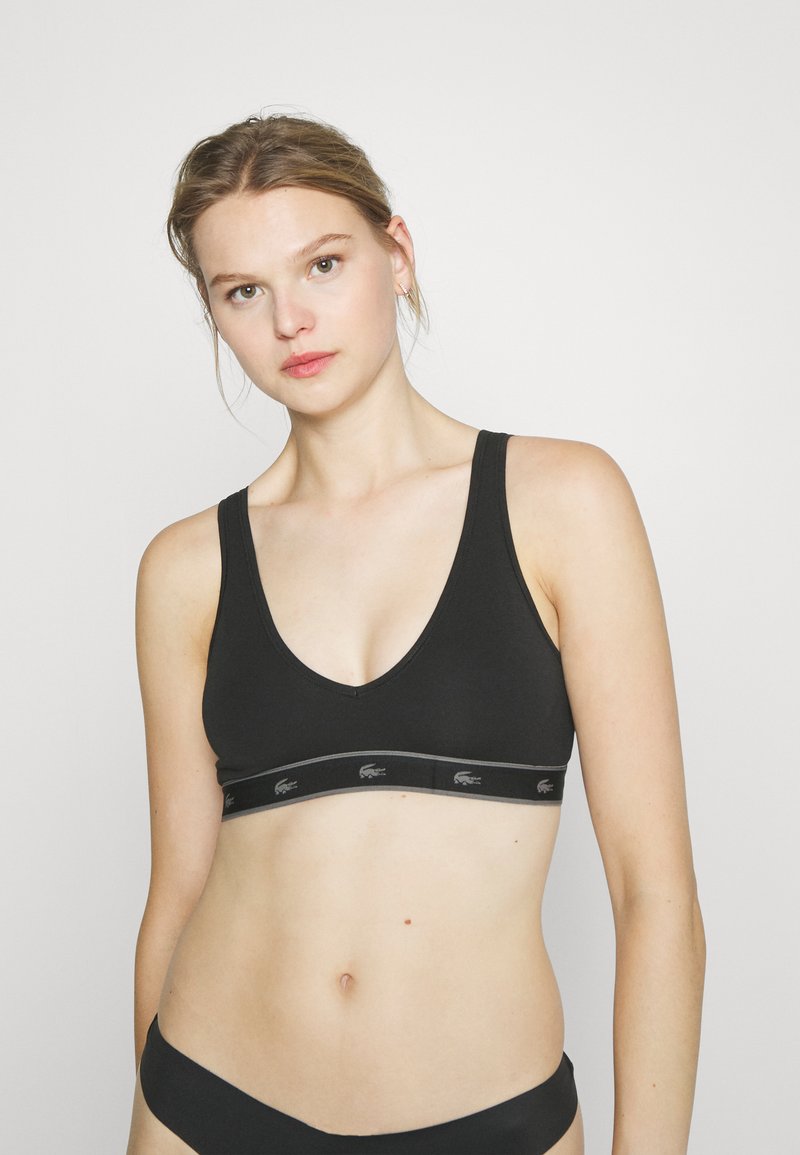 Čierny bavlnený bralet s výstrihom do V, širokými ramienkami a elastickým pásom s logom v sivej farbe. Hladká textúra.