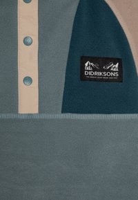 Fleece vršek s knoflíkovým zapínáním v světle béžové barvě, tyrkysovými akcenty a strukturovanou tkaninou. Štítek zobrazuje název značky "Didriksons" s logem.