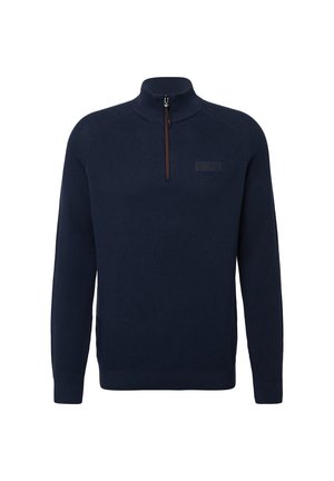 Jūras zilas adītas puloveris ar augsto apkakli un ceturtdaļas rāvējslēdzēju priekšā. Tam ir ribotas piedurknes un apakšmala, kā arī diskreta logotipa uzlīme uz krūtīm.