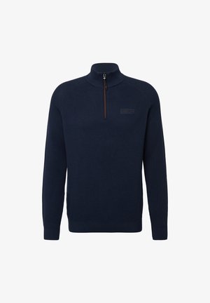 Jūras zilas adītas puloveris ar augsto apkakli un ceturtdaļas rāvējslēdzēju priekšā. Tam ir ribotas piedurknes un apakšmala, kā arī diskreta logotipa uzlīme uz krūtīm.