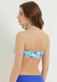 Biustonosz bikini bez ramiączek z niebiesko-zielonym wzorem kwiatowym, gładką fakturą i dopasowanym krojem. Proste niebieskie majtki uzupełniają górę.