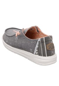 Scarpa slip-on in tela grigia con accenti a motivo, dettaglio in pizzo rosa e suola bianca. Presenta un retro texturizzato e una patch con logo.