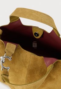 Borsa a tracolla in camoscio color cuoio con chiusura argento, tracolla larga e interno in pelle bordeaux, mostrata aperta dall'alto.