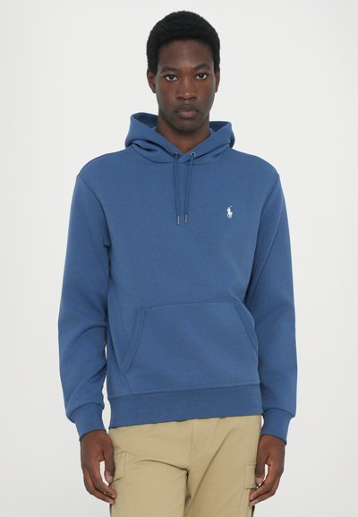 Tamsiai mėlyna puspalvis, pagamintas iš minkštos medvilnės mišinio, su priekinėmis kišenėmis, reguliuojama raištelių kapuce ir siuvinėtu logotipu kairėje krūtinės pusėje.