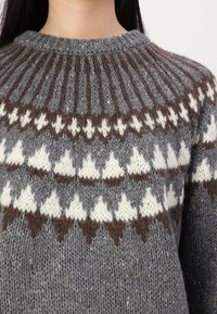 Pull en laine gris tricoté avec un col rond. Présente un motif en yoke avec des formes géométriques marron foncé et crème. Tissu en laine texturé.