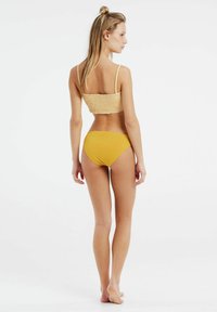 Geel bikiniset bestaande uit een gesmokte bralette-top met dunne bandjes en bijpassende hoge taille briefs, gemaakt van een gladde stof en met een minimalistisch ontwerp.