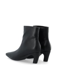 Bottines en cuir noir avec un bout pointu et un talon moyen incurvé. Texture lisse avec des accents minimalistes et un design épuré.