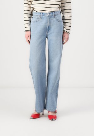 Light blue straight-leg jeans made of denim, featuring a high waist and subtle fading. Paired with red pointed-toe heels with metallic accents.