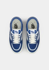 Blue suede sneakers featuring white leather accents, rounded toe, white laces, and branded insoles, showcasing a classic low-top design.