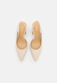 Beige spetsiga klackar med öppen bakdel och smala ankelsnören. Slät lädermaterial och en subtil präglad logotyp på innersulan.