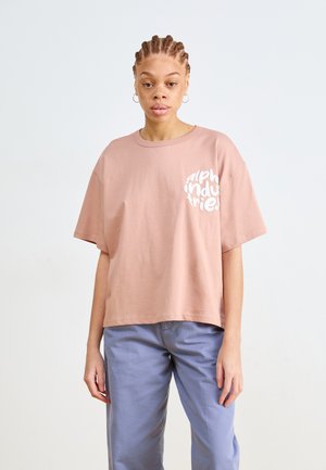 Ružová bavlnená tričko s krátkym rukávom a okrúhlym výstrihom, s bielym textom "alpha industries" potlačeným na ľavej strane hrudníka. Voľný strih.