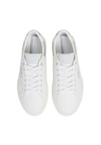 White canvas sneakers feature a smooth texture, round toe, and traditional lace-up design. Subtle branding accent on the side.
