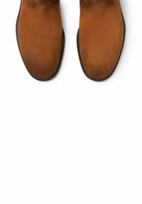 Botas de tobillo de ante marrón con una textura suave, punta redonda y una suela ligeramente elevada. Diseño simple sin herrajes o patrones visibles.