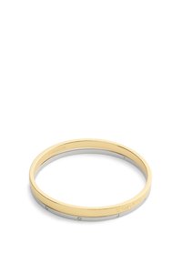 Brazalete de bangle en oro y plata, con un acabado metálico suave, presenta pequeñas piedras decorativas y un logotipo grabado en la sección de plata. Forma circular.