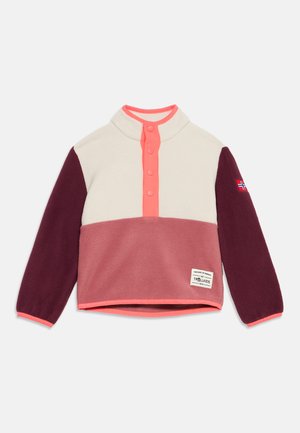 Pull polaire enfant avec haut crème, bas rose, manches bordeaux, patte de boutonnage pression rose et écusson avec drapeau norvégien sur la manche droite.