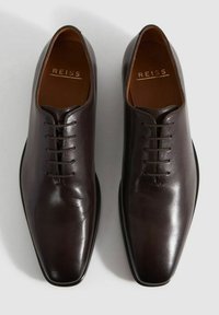 Braune Lederanzugschuhe mit einem schlanken, glatten Finish, runder Zehenform und sechs Ösen-Schnürung. Innenfutter ist hellbraun. Markenlogo sichtbar.