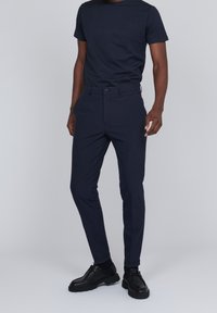 Navy blue short-sleeve t-shirt paired with tailored navy trousers. Trousers feature a button closure and slim-fit design, with smooth texture and no patterns.