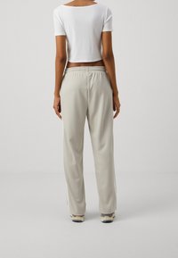 Ljusgrå sweatpants med elastisk midja, rak passform och sidofickor. Matchas med en kortärmad vit topp. Slät textur.