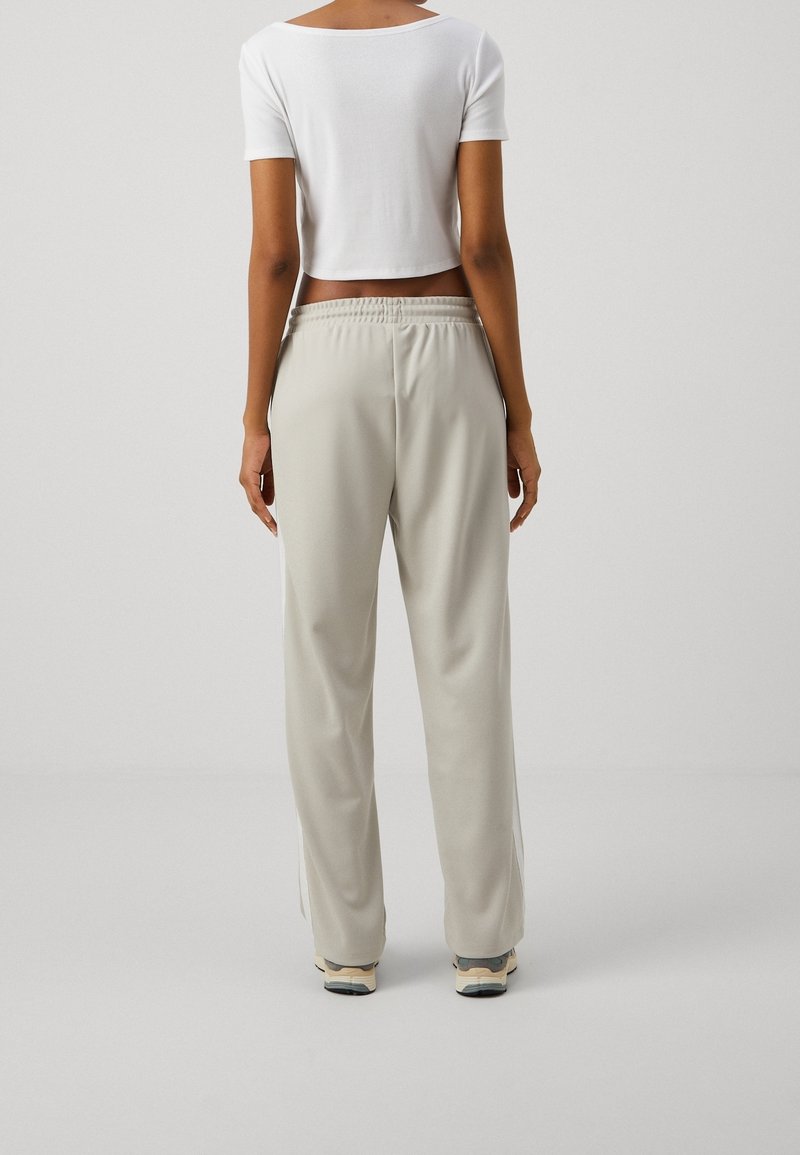 Ljusgrå sweatpants med elastisk midja, rak passform och sidofickor. Matchas med en kortärmad vit topp. Slät textur.