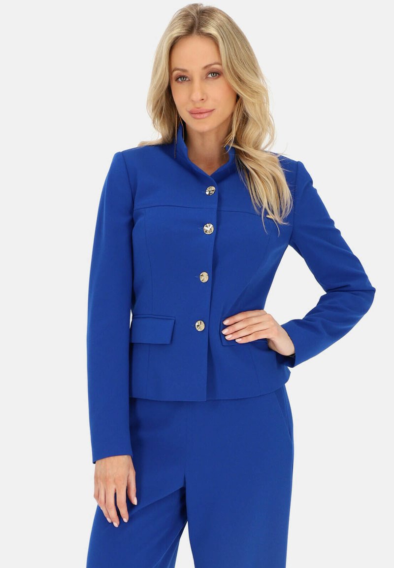 Niebieska dopasowana marynarka z wysokim kołnierzem, złotymi guzikami i wyraźnie zdefiniowanym kształtem. Posiada przednią kieszeń i gładką teksturę.