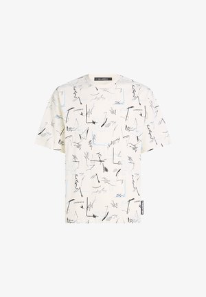 Valge lühikeste varrukatega T-särk, millel on must ja sinine abstraktne joonte muster, ümar kaelus ja silt vasakul küljel.