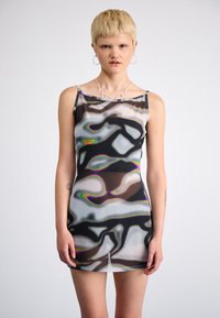 Robe mini transparente avec des motifs abstraits noir, blanc et multicolores. Présente un décolleté droit et des bretelles spaghetti. Texture lisse.