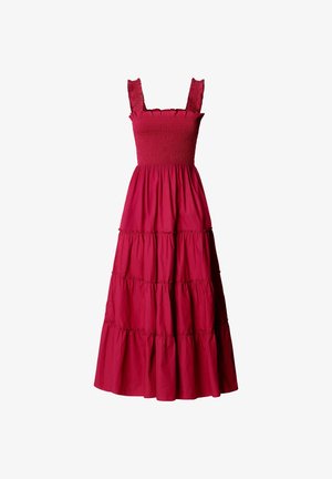 Hihaton punainen maxi-mekko, jossa pystyrysytetty yläosa, röyhelöiset olkaimet ja kerroksittain poimutettu hame valkoisella taustalla.