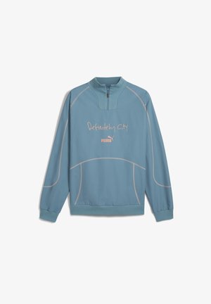 Suéter azul claro con cuello de media cremallera. Presenta el texto bordado en rosa "Definitely City" y un pequeño logo. Tejido suave y ligero.