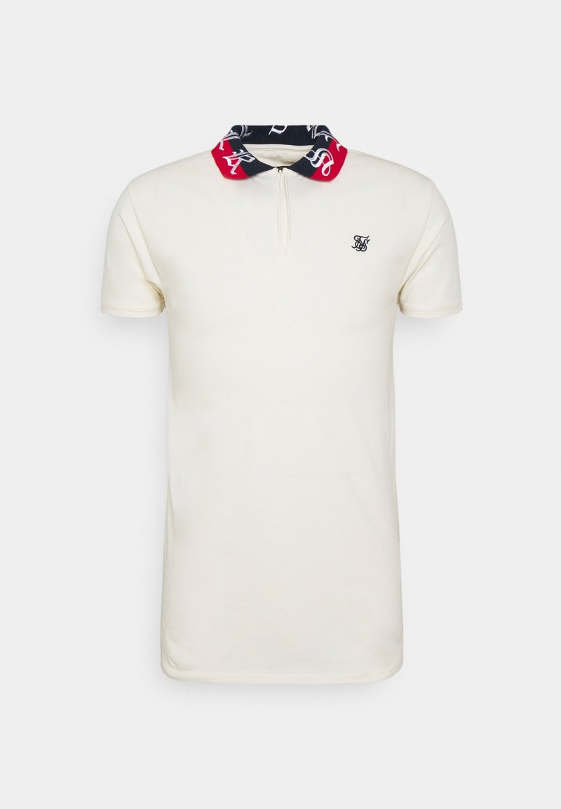 Polo blanc à manches courtes avec col bleu marine et rouge comportant une écriture blanche, fermeture éclair à l'avant, et petit logo noir brodé sur la poitrine.