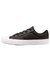 Sneaker in pelle nera con punta e suola in gomma bianca, caratterizzato da lacci neri e un sottile logo a stella sul lato esterno. Forma rotonda.
