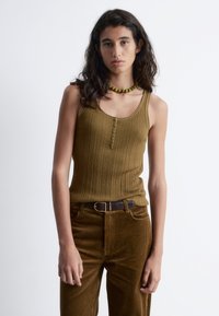 Olive green ribbed tank top with a henley neckline featuring buttons; paired with matching corduroy pants and a dark belt.