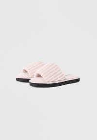 Zapatillas de terciopelo rosa con diseño superior acanalado, estilo de punta abierta y suela de goma negra para contraste. Textura suave y apariencia casual.
