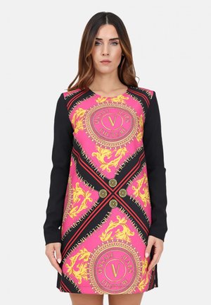 Abito rosa colorato con maniche lunghe nere, caratterizzato da motivi dorati, logo circolare e un bordo nero a contrasto lungo i bordi.