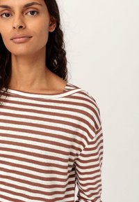 Top de manga larga a rayas marrón y blanco con un escote amplio y textura suave, que cuenta con costuras de hombro caídas para un ajuste relajado.