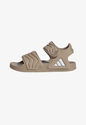 Beige sandaal met open teen, twee gevoerde verstelbare banden en een wit logo met drie strepen aan de zijkant.