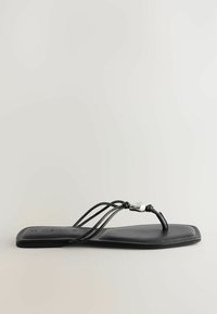 Sandale plate noire à bout carré, fines brides triples et détail en perles argentées sur un fond uni.