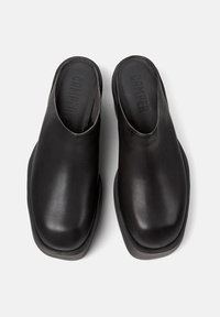 Mule din piele neagră cu spate deschis, vârf rotund și design minimalist, având o textură netedă și un toc din cauciuc de contrast.
