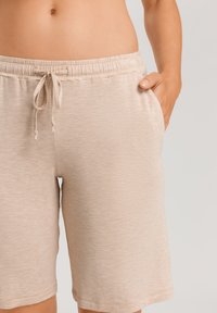 Beige, strukturerade shorts med elastisk midja och dragsko. Har sidofickor och en avslappnad passform, som når strax ovanför knäet.