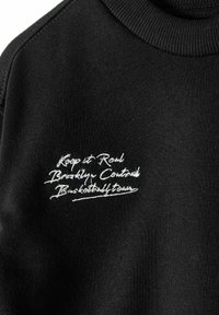 Felpa nera con collo a coste e dettagli in bianco ricamati: "Keep it Real Brooklyn Central Basketball Team." Tessuto morbido.