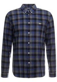 Camisa de manga larga abotonada con patrón a cuadros en azul, negro y gris, y pequeño logo de cocodrilo verde en el lado izquierdo del pecho.