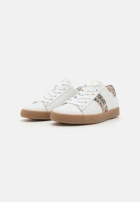Vita sneakers i läder med en texturerad brun gummisula, med en leopardmönstrad detalj på sidan och vita snören.